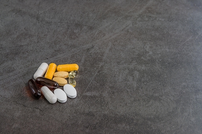 Collection of various vitamins in both pills and gelcap on black textured background, by aminkorea
