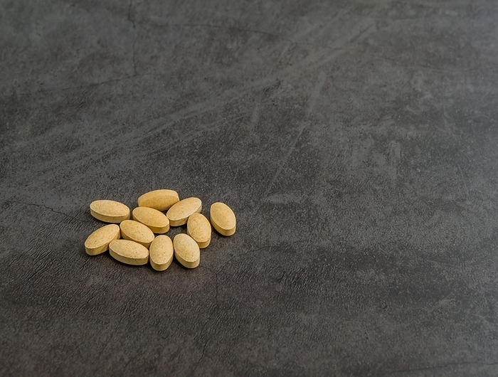 Closeup of vitamin C tablets isolated on black textured background, by aminkorea