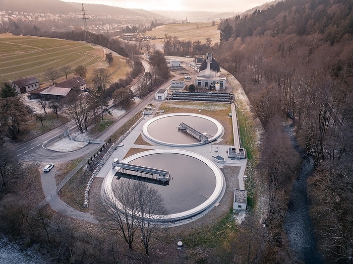 Drone shot of a sewage treatment plant with round basins in a gentle landscape at dusk, Nagold, Black Forest, Germany, Europe, by Manuel Kamuf