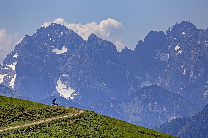 Mountain biker in front of steep mountains, noon, summer, Kaiser Mountains, Tyrol, Austria, Europe, by Martina Melzer