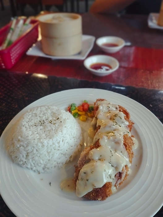A plate of rice with chicken cordon bleu and mixed vegetables topped with creamy sauce, by MartinxMarie
