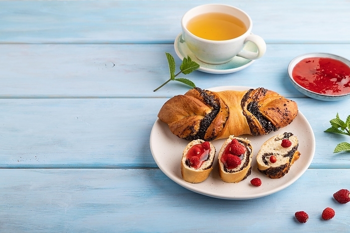 Homemade sweet bun with strawberry jam and cup of green tea on a blue wooden background. side view, copy space, by ULADZIMIR ZGURSKI