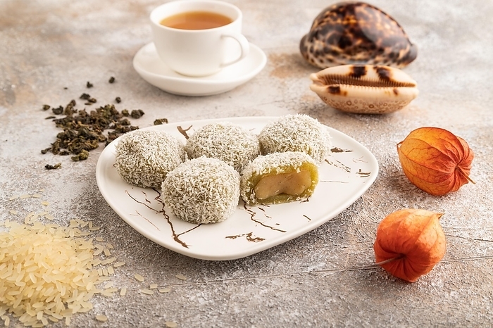 Japanese rice sweet buns mochi filled with pandan jam and cup of green tea on brown concrete background. side view, close up, by ULADZIMIR ZGURSKI