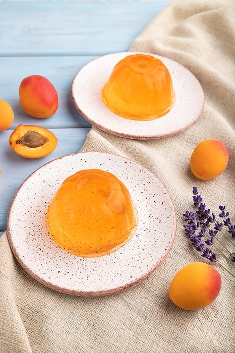 Apricot orange jelly on blue wooden background and linen textile. side view, close up, by ULADZIMIR ZGURSKI