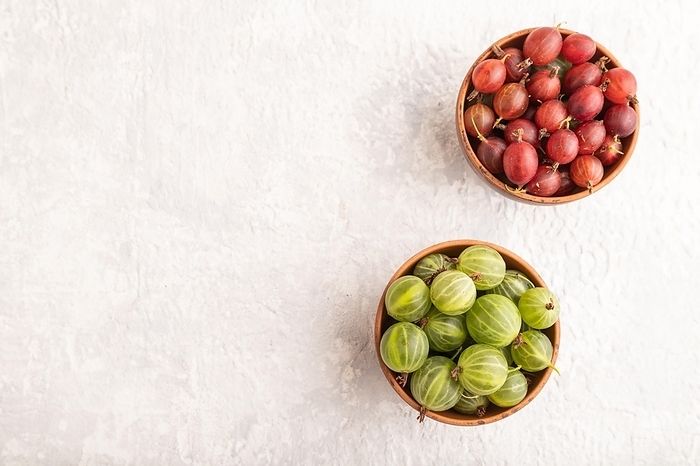 Fresh red and green gooseberry in clay bowl on gray concrete background. top view, flat lay, copy space, by ULADZIMIR ZGURSKI