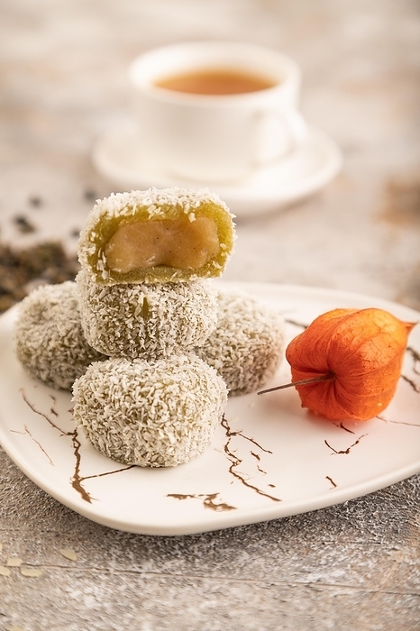 Japanese rice sweet buns mochi filled with pandan jam and cup of green tea on brown concrete background. side view, close up, selective focus, by ULADZIMIR ZGURSKI