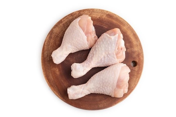 Raw chicken legs on a wooden cutting board isolated on white background. Top view, flat lay, close up, by ULADZIMIR ZGURSKI
