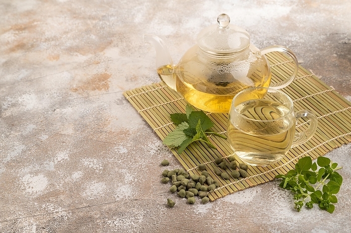 Green oolong tea with herbs in glass on brown concrete background. Healthy drink concept. Side view, copy space, by ULADZIMIR ZGURSKI