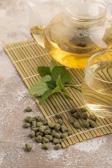 Green oolong tea with herbs in glass on brown concrete background. Healthy drink concept. Side view, close up, by ULADZIMIR ZGURSKI