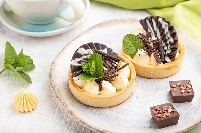 Sweet tartlets with chocolate and cheese cream with cup of coffee on a gray concrete background and green textile. Side view, close up, by ULADZIMIR ZGURSKI