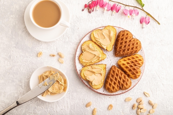 Homemade waffle with peanut butter and cup of coffee on a gray concrete background. top view, flat lay, close up, by ULADZIMIR ZGURSKI