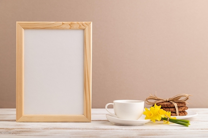 Wooden frame with oatmeal cookies yellow narcissus and coffee cup on beige pastel background. side view, copy space, still life, mockup, template, spring minimalism concept, by ULADZIMIR ZGURSKI