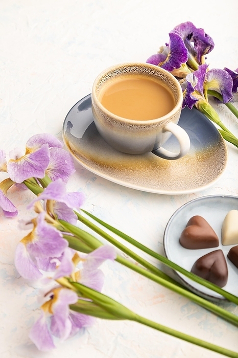 Cup of cioffee with chocolate candies and lilac iris flowers on white concrete background. side view, close up, still life. Breakfast, morning, spring concept, by ULADZIMIR ZGURSKI