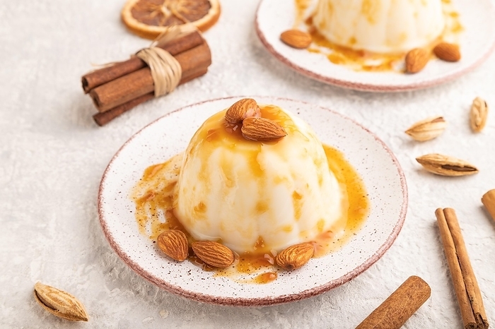 White milk jelly with caramel sauce on gray concrete background. side view, close up, by ULADZIMIR ZGURSKI