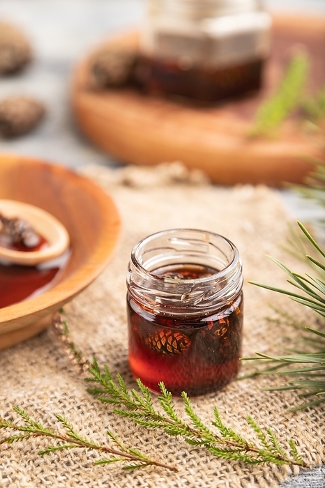 Pine cone jam with herbal tea on gray wooden background and linen textile. Side view, close up, selective focus, by ULADZIMIR ZGURSKI