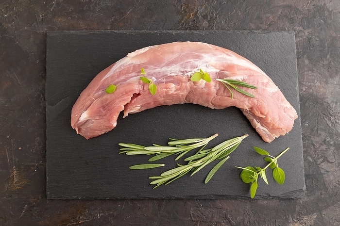 Raw pork meat with herbs and spices on slate cutting board on black concrete background. Top view, flat lay, close up, by ULADZIMIR ZGURSKI