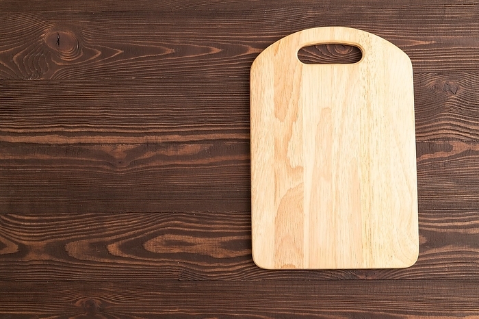 Empty rectangular wooden cutting board on brown wooden background. Top view, copy space, flat lay, by ULADZIMIR ZGURSKI