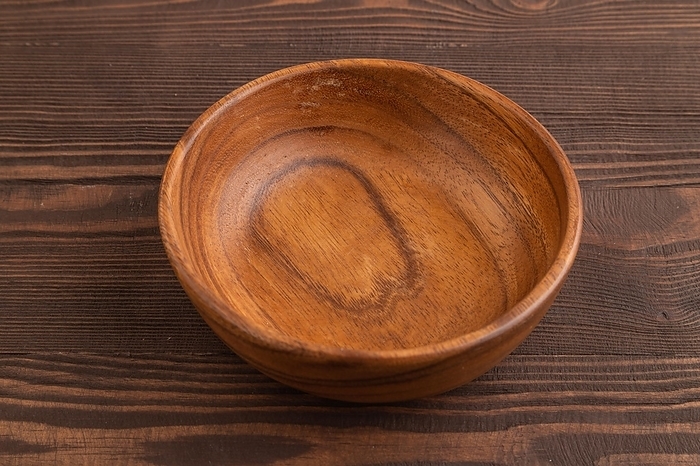 Empty brown wooden bowl on brown wooden background. Side view, copy space, by ULADZIMIR ZGURSKI
