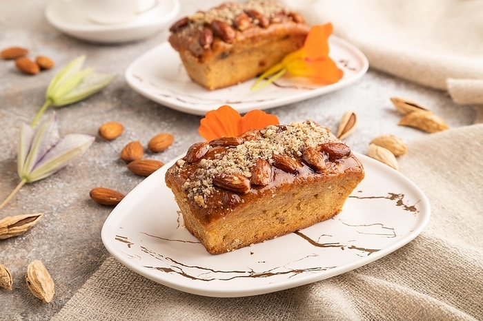 Caramel and almond cake with cup of coffee on brown concrete background and linen textile. side view, close up, by ULADZIMIR ZGURSKI