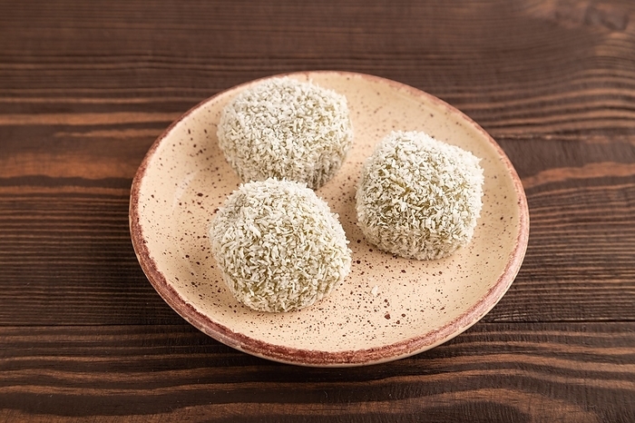 Japanese rice sweet buns mochi filled with pandan and coconut jam on brown wooden background. side view, close up, by ULADZIMIR ZGURSKI
