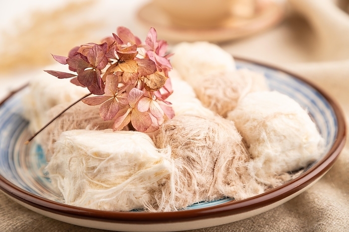 Traditional arabic sweets pishmanie and a cup of green tea on white wooden background and linen textile. side view, close up, selective focus, by ULADZIMIR ZGURSKI