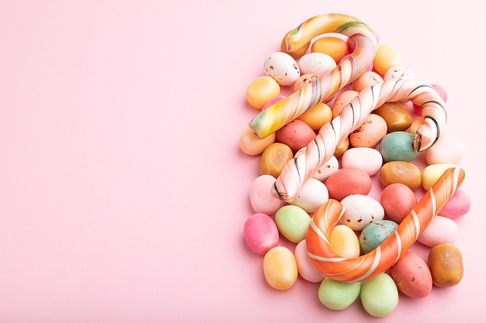 Various caramel candies on pink pastel background. copy space, side view, by ULADZIMIR ZGURSKI
