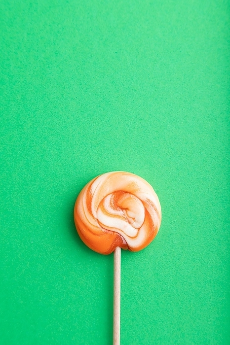 Single lollipop candy on green pastel background. copy space, top view, flat lay, by ULADZIMIR ZGURSKI