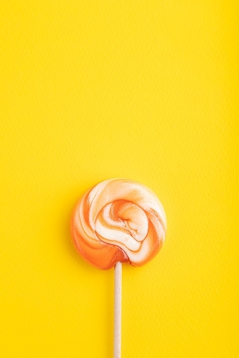 Single lollipop candy on yellow pastel background. copy space, top view, flat lay, by ULADZIMIR ZGURSKI