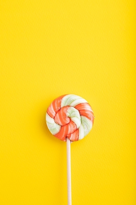 Single lollipop candy on yellow pastel background. copy space, top view, flat lay, by ULADZIMIR ZGURSKI