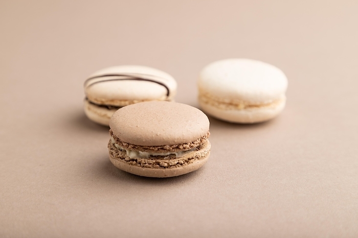 Brown and white macaroons on beige pastel background. side view, close up, still life. Breakfast, morning, concept, by ULADZIMIR ZGURSKI
