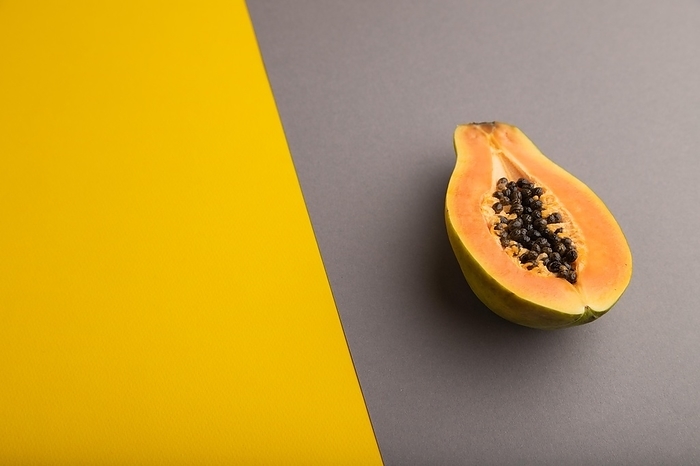 Ripe cut papaya on yellow and gray pastel background. Side view, copy space. Tropical, healthy food, women health concept, minimalism, by ULADZIMIR ZGURSKI