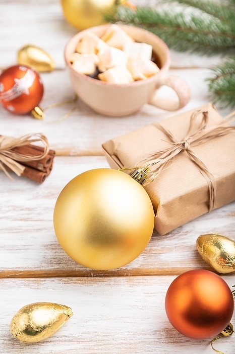 Christmas or New Year composition. Decorations, box, golden balls, cinnamon, fir and spruce branches, cup of coffee, on a white wooden background. Side view, close up, selective focus, by ULADZIMIR ZGURSKI
