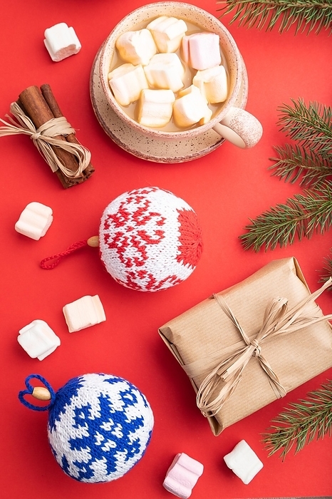 Christmas or New Year composition. Decorations, box, cinnamon, knitted balls, fir and spruce branches, cup of coffee, on a red paper background. Top view, close up, flat lay, by ULADZIMIR ZGURSKI