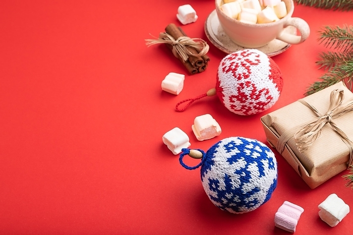 Christmas or New Year composition. Decorations, box, cinnamon, knitted balls, fir and spruce branches, cup of coffee, on a red paper background. Side view, copy space, by ULADZIMIR ZGURSKI