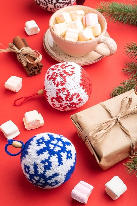 Christmas or New Year composition. Decorations, box, cinnamon, knitted balls, fir and spruce branches, cup of coffee, on a red paper background. Side view, close up, by ULADZIMIR ZGURSKI