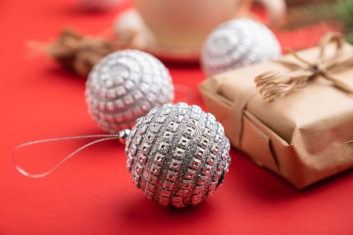 Christmas or New Year composition. Decorations, box, cinnamon, silver balls, fir and spruce branches, cup of coffee, on a red paper background. Side view, close up, selective focus, by ULADZIMIR ZGURSKI
