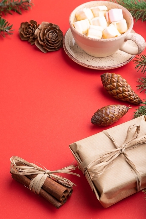 Christmas or New Year composition. Decorations, box, cinnamon, cones, fir and spruce branches, cup of coffee, on a red paper background. Side view, copy space, by ULADZIMIR ZGURSKI