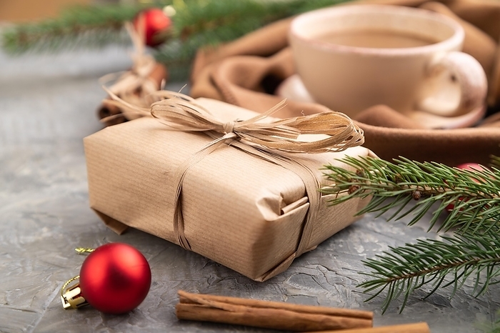 Christmas or New Year composition. Decorations, box, cinnamon, fir and spruce branches, cup of coffee, wool scarf on a gray concrete background. Side view, close up, selective focus, by ULADZIMIR ZGURSKI