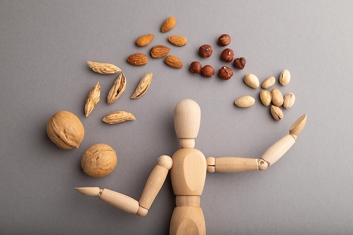 Wooden mannequin juggling nuts on gray pastel background. close up, isolated, delivery concept, by ULADZIMIR ZGURSKI