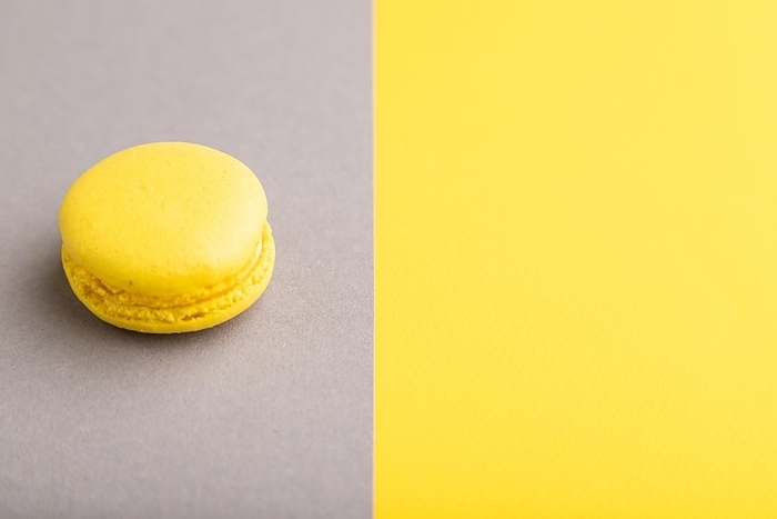 Yellow macaroon on trendy gray and yellow background. side view, copy space, close up, still life. Minimalism, morning, contrast concept, by ULADZIMIR ZGURSKI