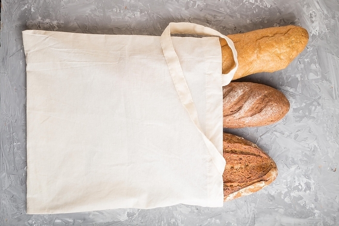 Reusable textile grocery bag with fresh baked bread on a gray concrete background. top view, flat lay, copy space. zero waste concept, by ULADZIMIR ZGURSKI