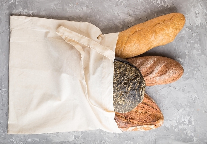 Reusable textile grocery bag with fresh baked bread on a gray concrete background. top view, flat lay, copy space. zero waste concept, by ULADZIMIR ZGURSKI