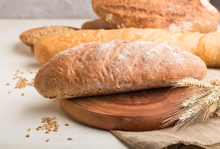 Different kinds of fresh baked bread on a white wooden background. side view, close up, selective focus, by ULADZIMIR ZGURSKI