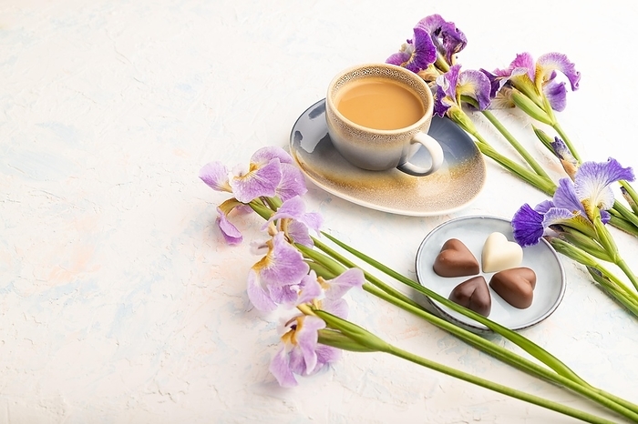 Cup of cioffee with chocolate candies and lilac iris flowers on white concrete background. side view, copy space, still life. Breakfast, morning, spring concept, by ULADZIMIR ZGURSKI