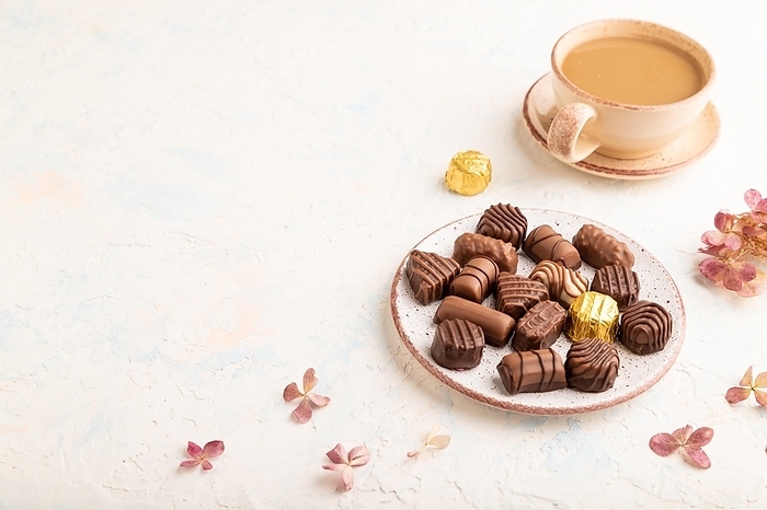 Chocolate candies with cup of coffee and hydrangea flowers on a white concrete background. side view, copy space, by ULADZIMIR ZGURSKI