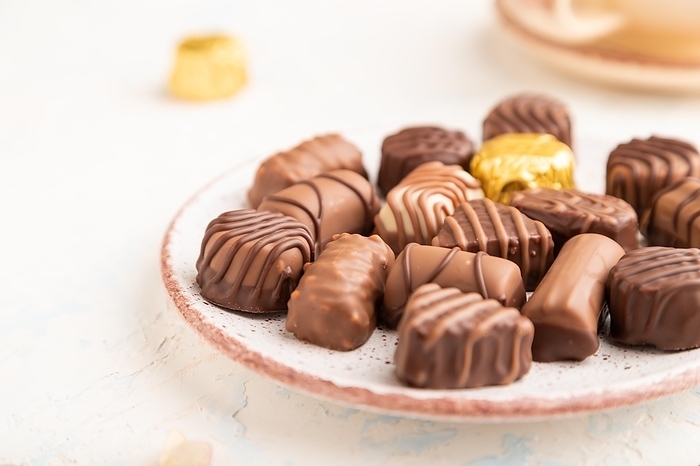 Chocolate candies with cup of coffee and hydrangea flowers on a white concrete background. side view, close up, selective focus, by ULADZIMIR ZGURSKI
