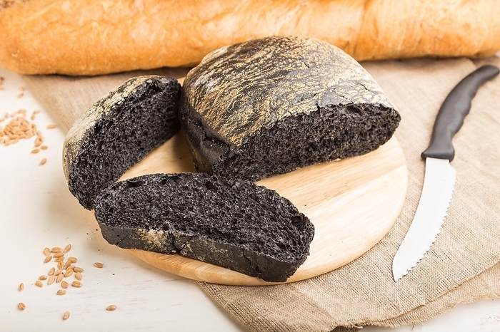 Sliced black bread with different kinds of fresh baked bread on a white wooden background. side view, close up, selective focus, by ULADZIMIR ZGURSKI