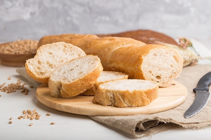 Sliced bread with different kinds of fresh baked bread on a white wooden background. side view, close up, selective focus, by ULADZIMIR ZGURSKI
