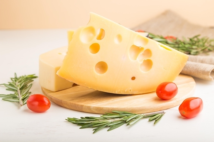Various types of cheese with rosemary and tomatoes on wooden board on a white wooden background and linen textile. Side view, close up, selective focus, by ULADZIMIR ZGURSKI
