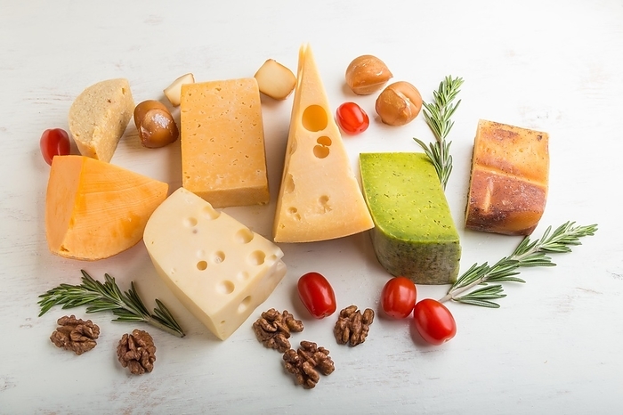 Set of different types of cheese with rosemary and tomatoes on a white wooden background. Side view, close up, by ULADZIMIR ZGURSKI